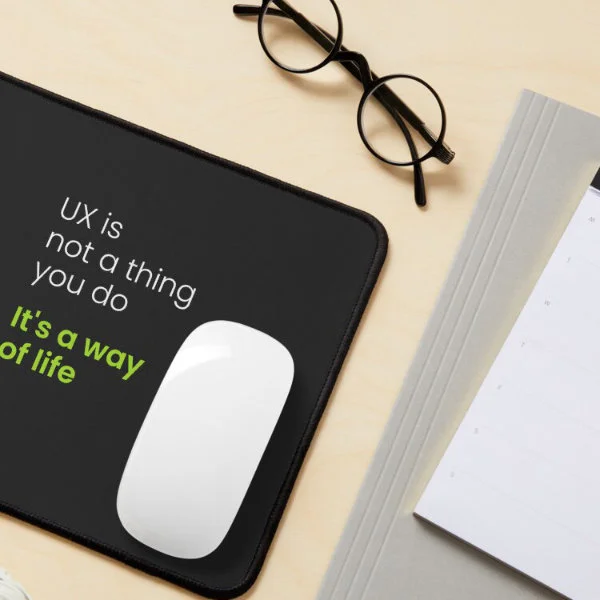 A mouse pad with the phrase "UX is not a thing you do, it&rsquo;s a way of life" in white and green letters.