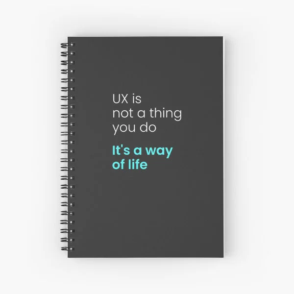 A spiral notebook with the phrase "UX is not a thing you do, it&rsquo;s a way of life" in white and turquoise letters.